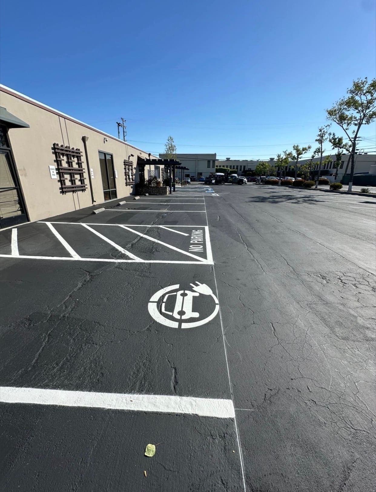 Freshly painted EV charging stall stencil and no-parking hatching in a commercial parking lot