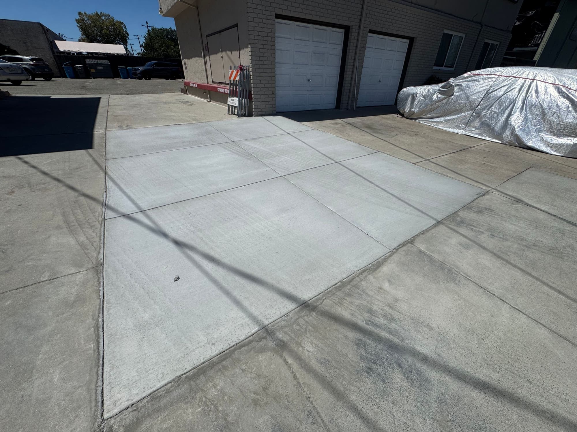 Finished concrete drive apron with broom finish and saw-cut control joints poured by Paragon General Engineering