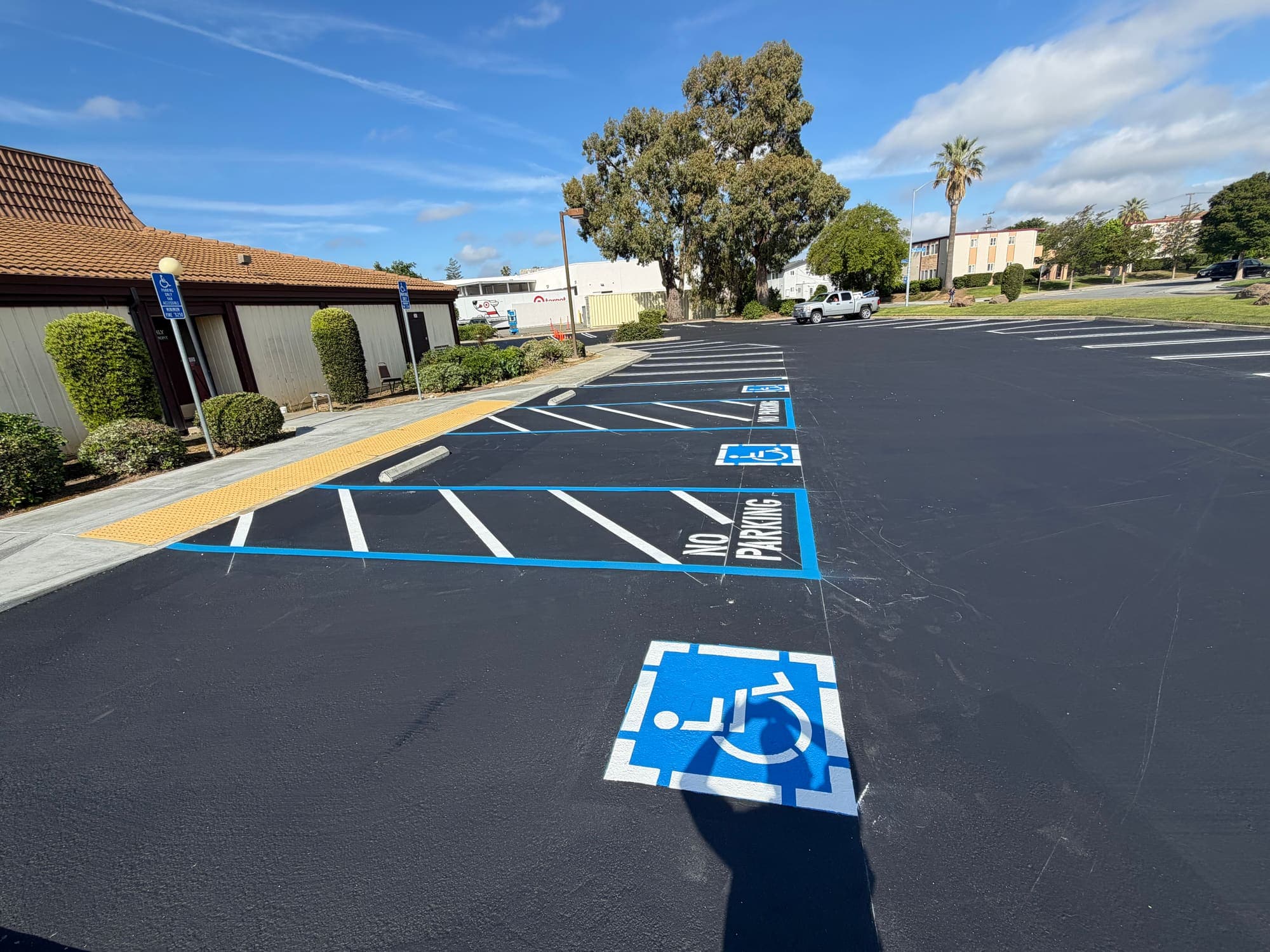 Wide view of a resurfaced parking lot with new ADA stalls, access aisles, and directional striping